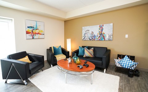 a living room with black couches and a round table